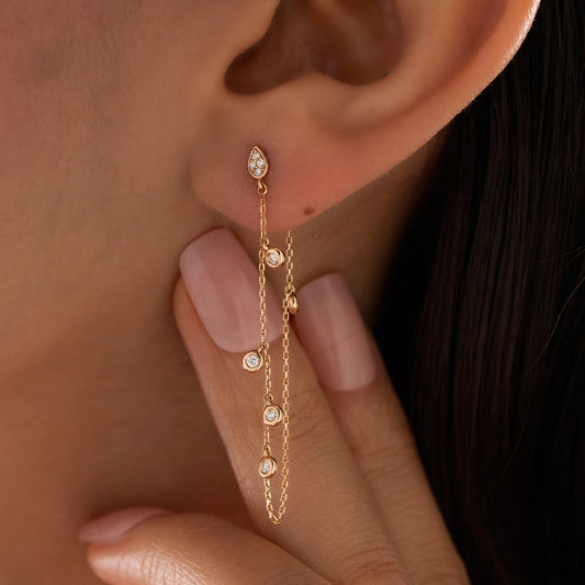 Arel Custom Jewelry 14k solid gold drape chain earring featuring a diamond teardrop stud and bezel diamonds on a model.