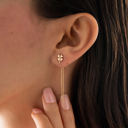 Arel Custom Jewelry 14k solid gold clover earrings with a center diamond and dangling chains on model's ear.