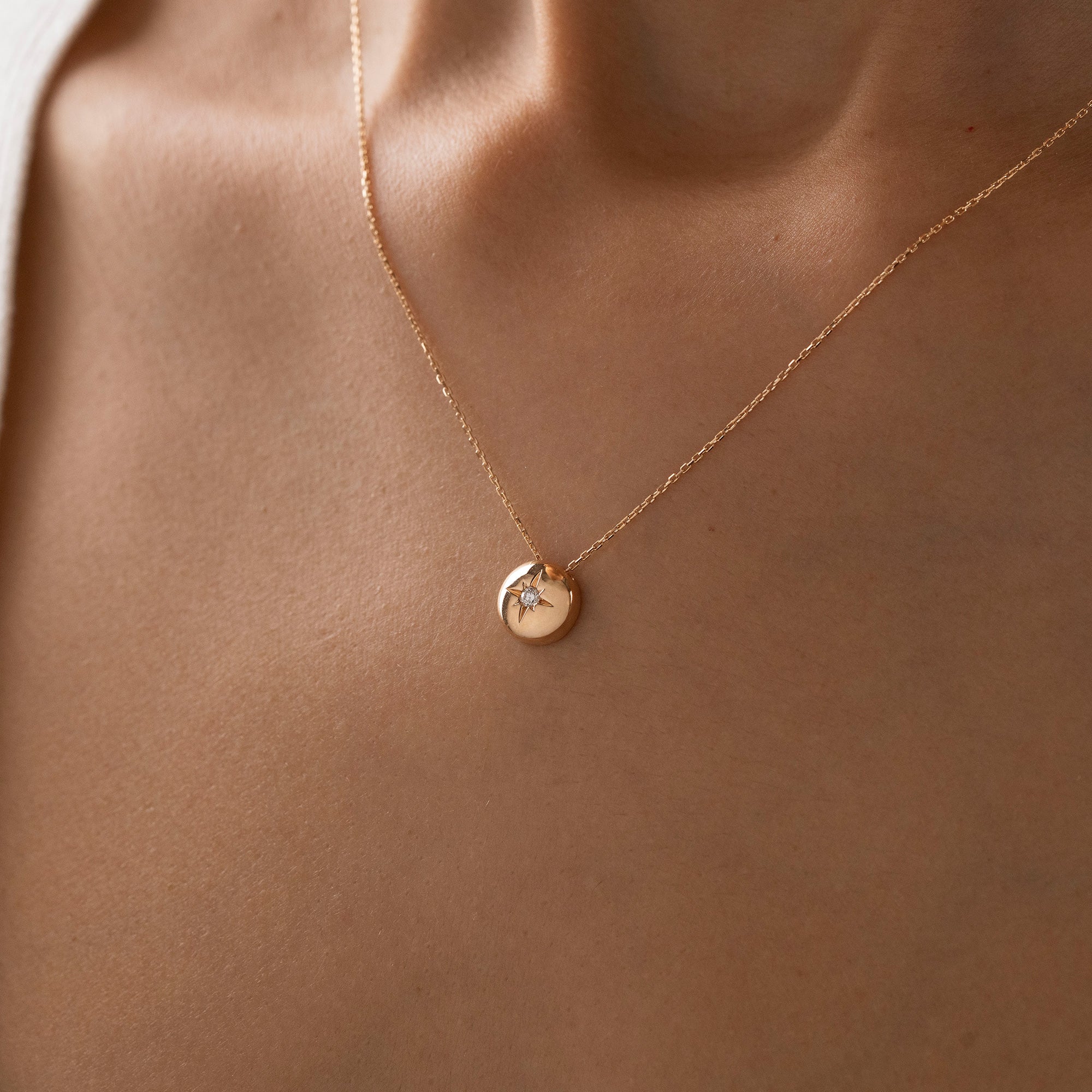 Arel Custom Jewelry 14k solid gold necklace featuring a polished domed pendant with a starburst set center diamond on a model.