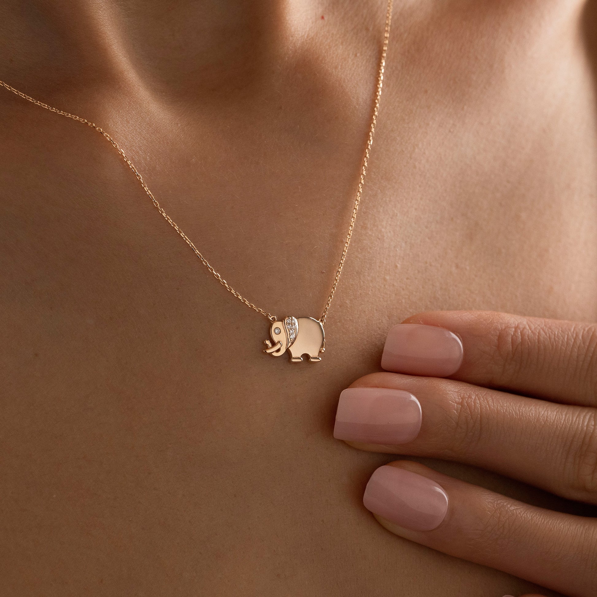 Arel Custom Jewelry 14k solid gold necklace featuring a polished elephant pendant with a pave diamond ear and trunk up on a model.