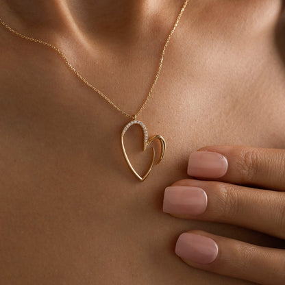 Arel Custom Jewelry 14k solid gold asymmetrical open heart necklace featuring half pave diamonds on a model.