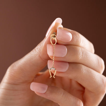 Arel Custom Jewelry 14k solid gold drop earring featuring an oval loop stud and dangling diamond horseshoe charm on a model.