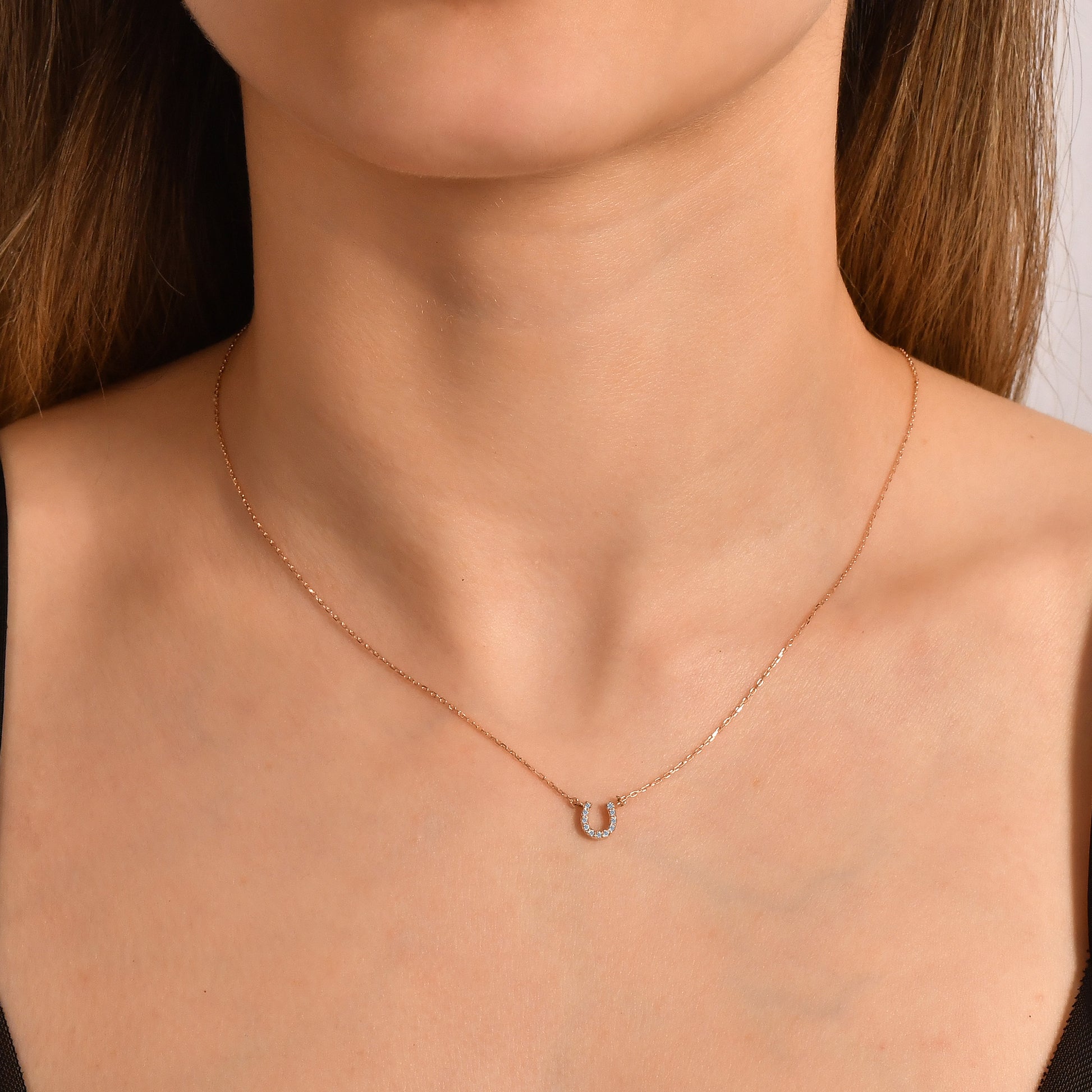 Arel Custom Jewelry 14k solid gold dainty necklace featuring a stationary pave diamond horseshoe pendant on a model.