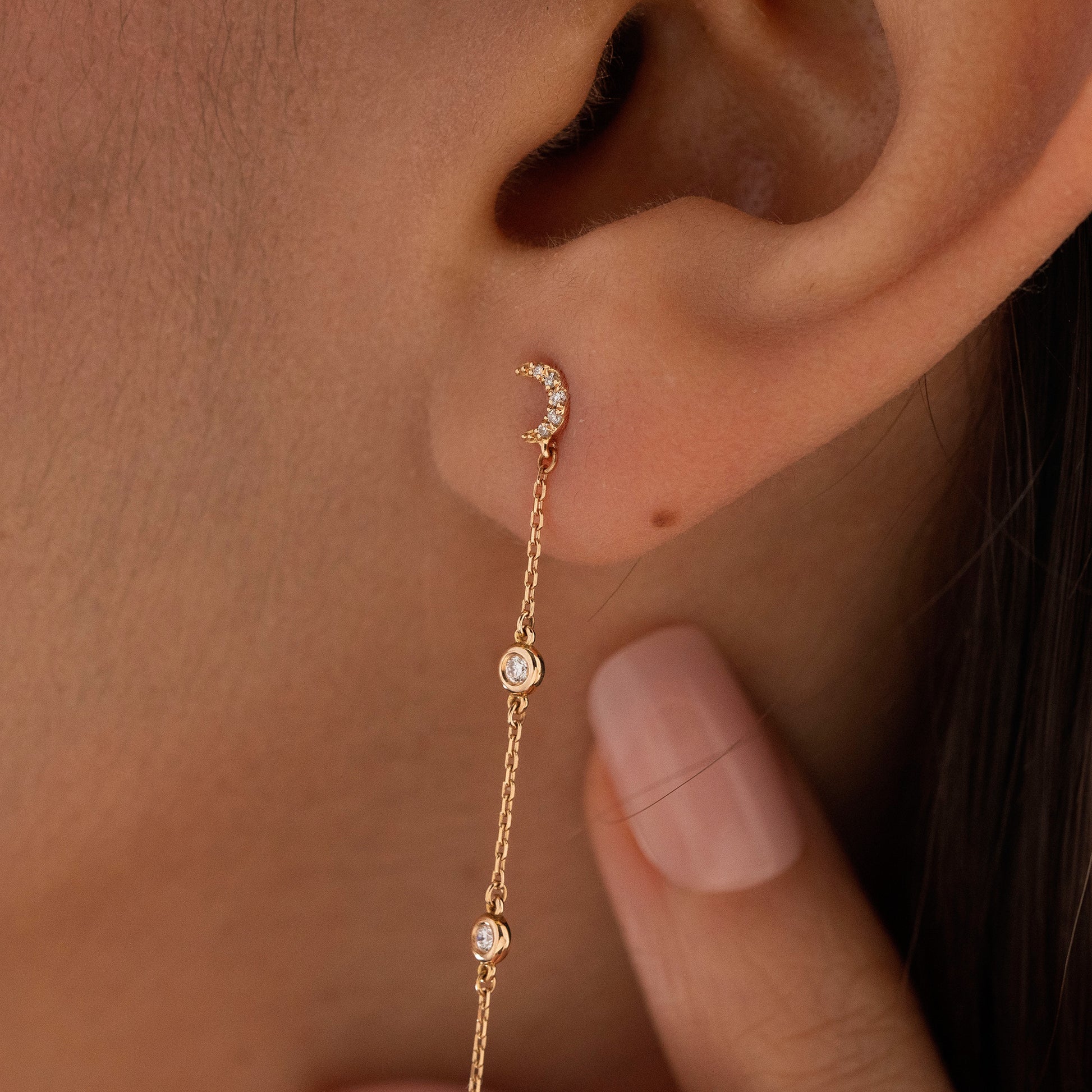 Arel Custom Jewelry 14k solid gold celestial crescent moon drop earring with dangling bezel set diamonds on a model.