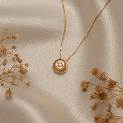 Arel Custom Jewelry 14k solid gold necklace featuring a polished domed pendant with a starburst set center diamond on a model.