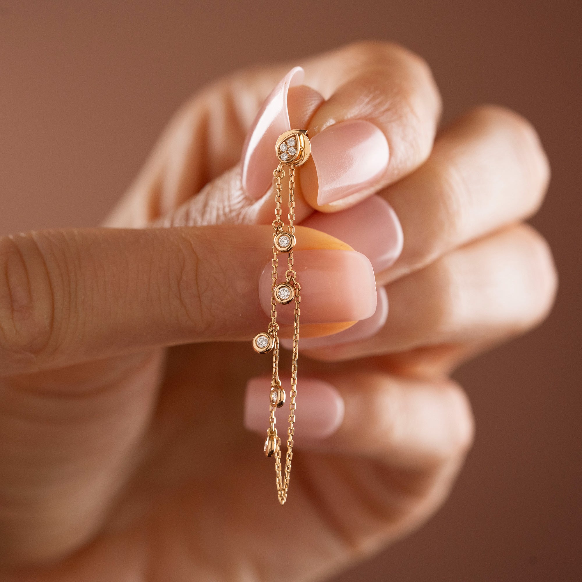 Arel Custom Jewelry 14k solid gold drape chain earring featuring a diamond teardrop stud and bezel diamonds on a model.