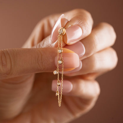 Arel Custom Jewelry 14k solid gold drape chain earring featuring a diamond teardrop stud and bezel diamonds on a model.