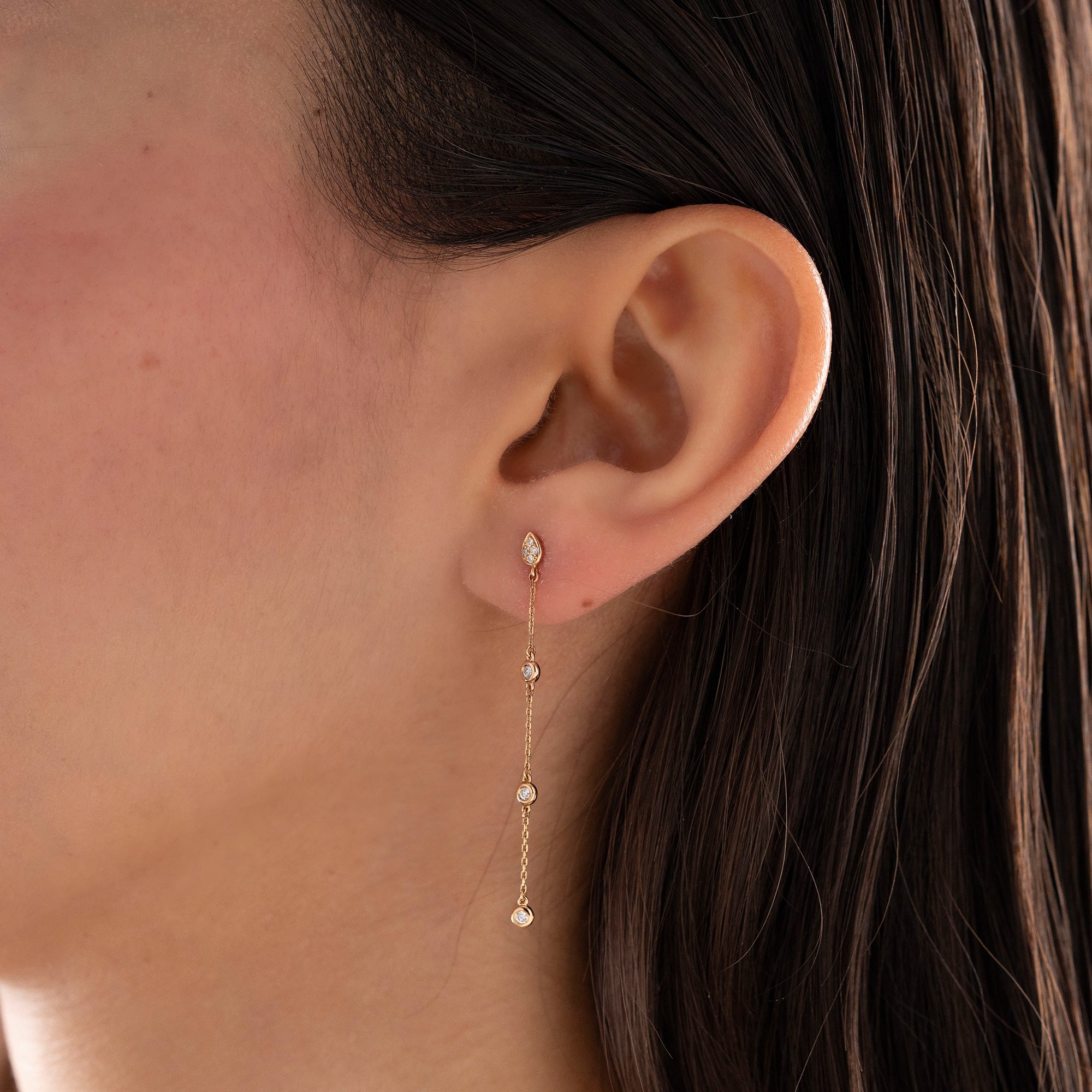 Arel Custom Jewelry 14k solid gold teardrop earring with natural diamonds on a dangling chain, worn by a model.