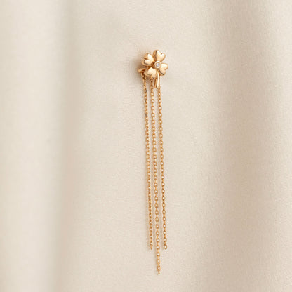 Arel Custom Jewelry 14k solid gold clover earrings with a center diamond and dangling chains on model's ear.