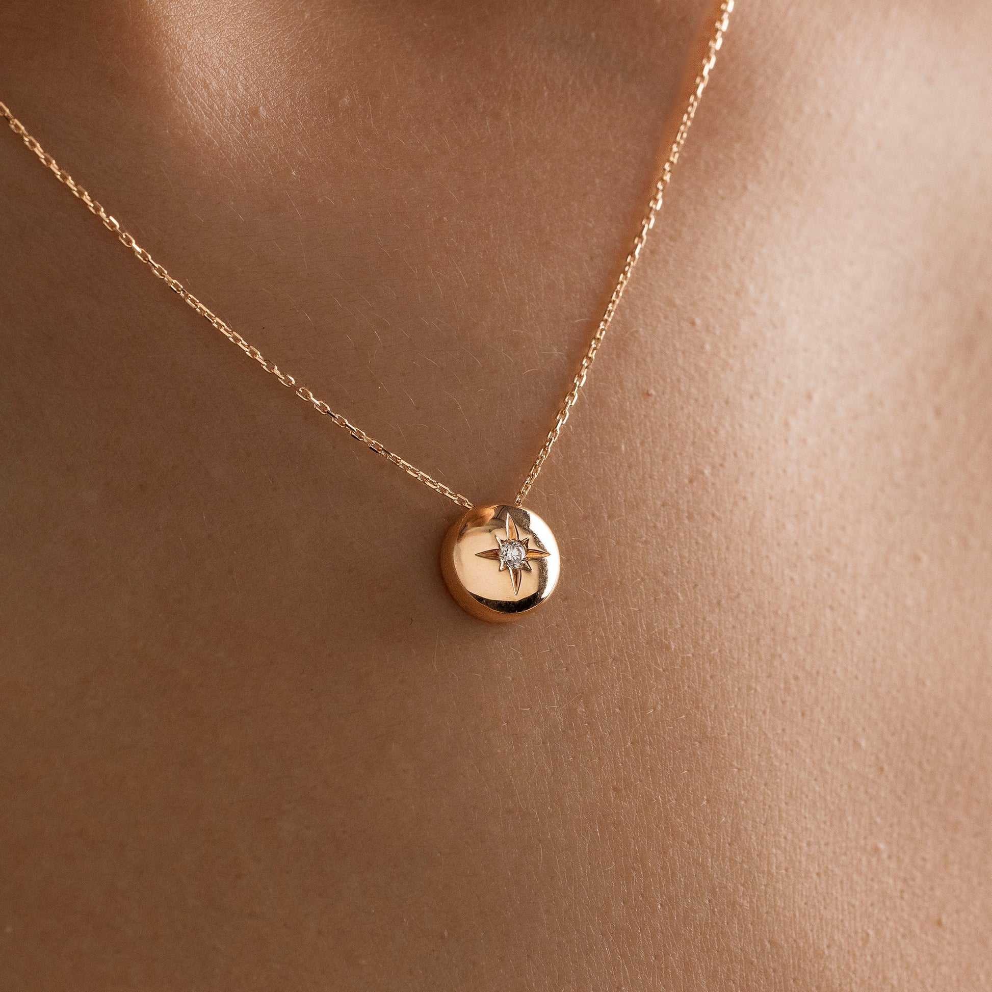 Arel Custom Jewelry 14k solid gold necklace featuring a polished domed pendant with a starburst set center diamond on a model.