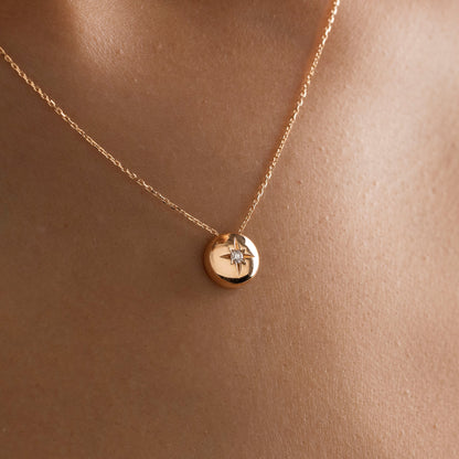 Arel Custom Jewelry 14k solid gold necklace featuring a polished domed pendant with a starburst set center diamond on a model.