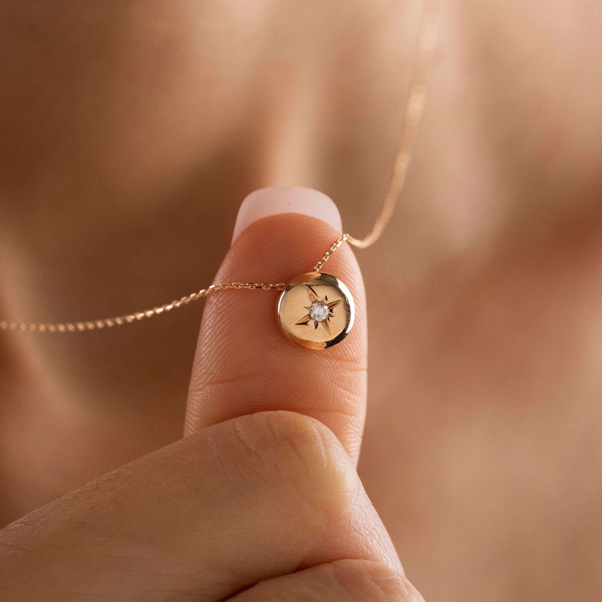 Arel Custom Jewelry 14k solid gold necklace featuring a polished domed pendant with a starburst set center diamond on a model.