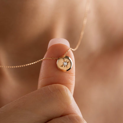 Arel Custom Jewelry 14k solid gold necklace featuring a polished domed pendant with a starburst set center diamond on a model.