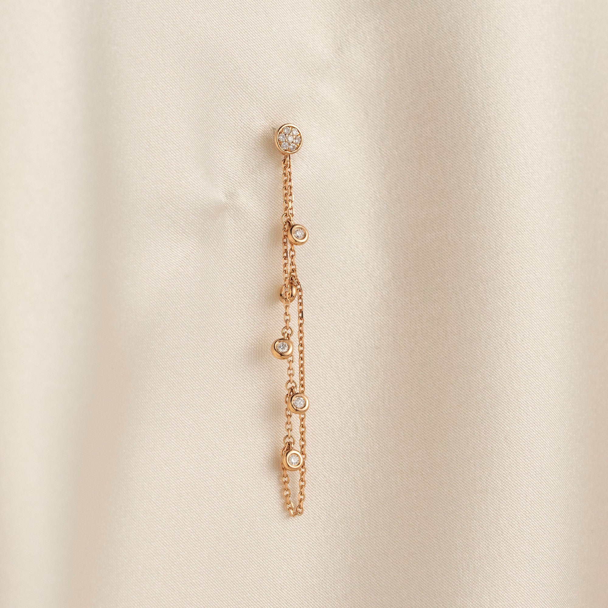 14k solid gold chain bezel earring featuring a round diamond stud and 5 diamond drops on a model.