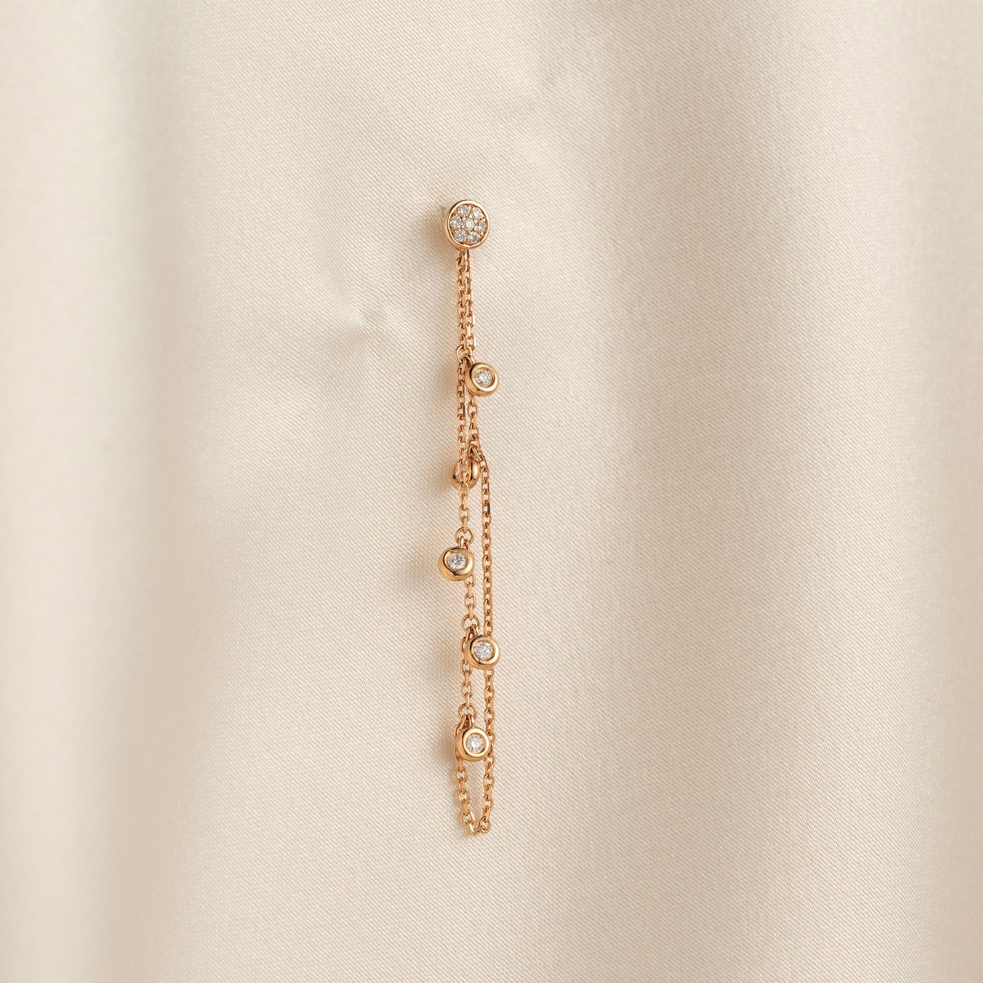 14k solid gold chain bezel earring featuring a round diamond stud and 5 diamond drops on a model.
