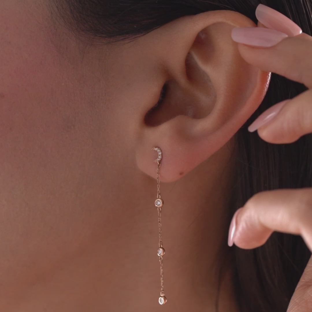 Arel Custom Jewelry 14k solid gold celestial crescent moon drop earring with dangling bezel set diamonds on a model.