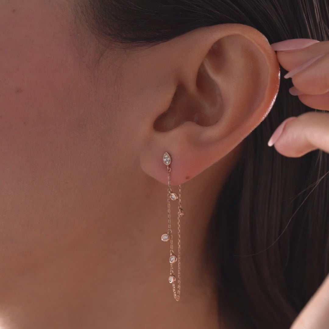 Arel Custom Jewelry 14k solid gold drape chain earring featuring a diamond teardrop stud and bezel diamonds on a model.