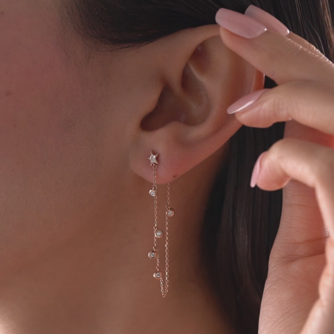 Dainty 14k gold front-to-back chain earring featuring a diamond star stud and bezel-set diamond drops on a model.
