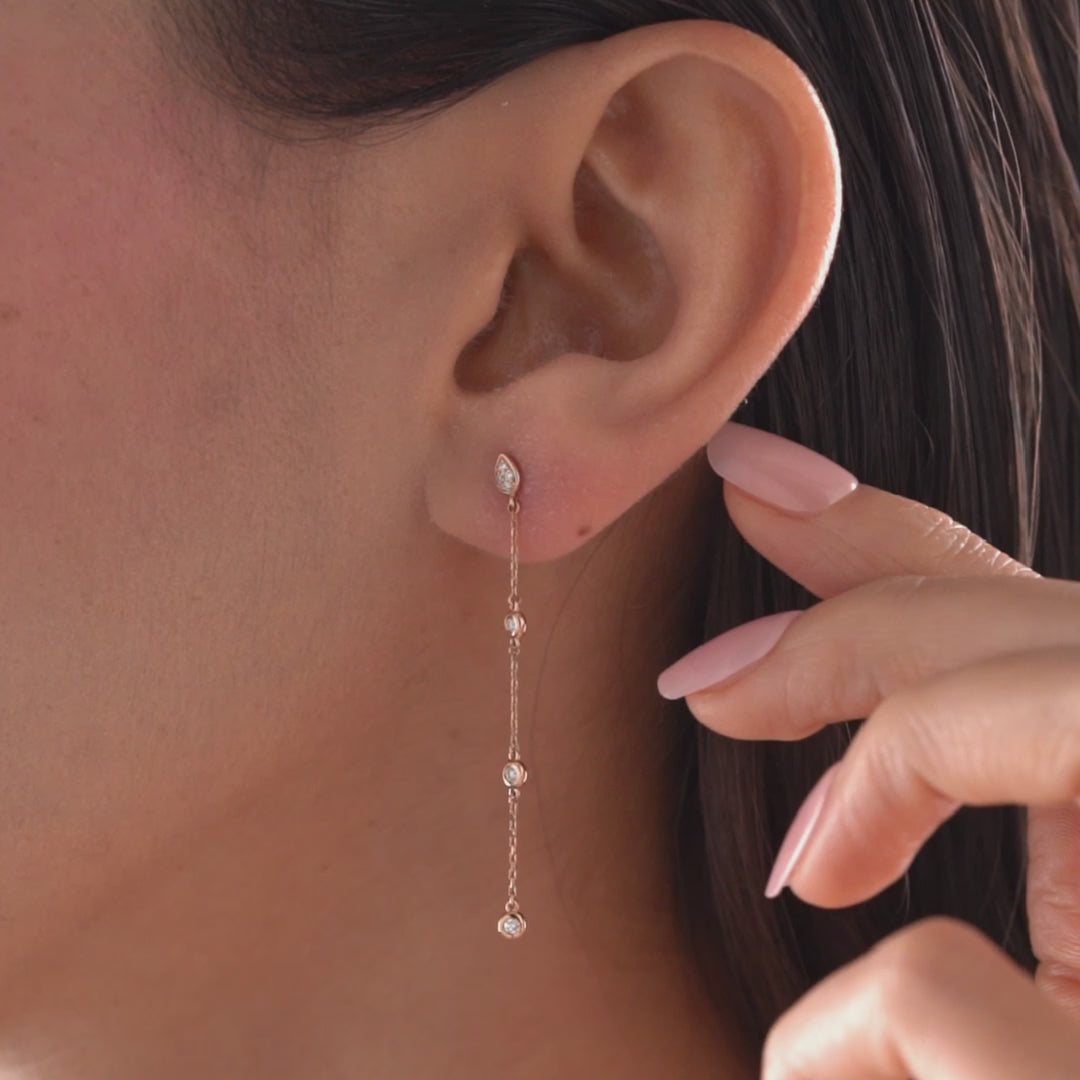 Arel Custom Jewelry 14k solid gold teardrop earring with natural diamonds on a dangling chain, worn by a model.