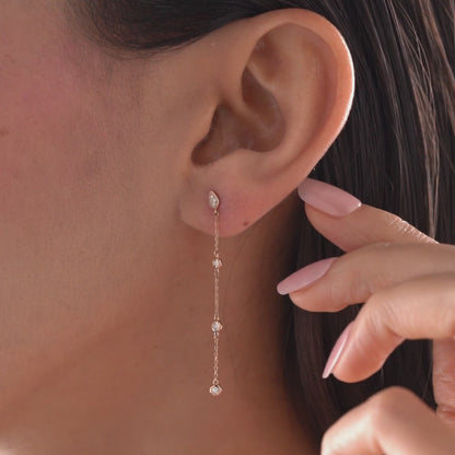 Arel Custom Jewelry 14k solid gold teardrop earring with natural diamonds on a dangling chain, worn by a model.