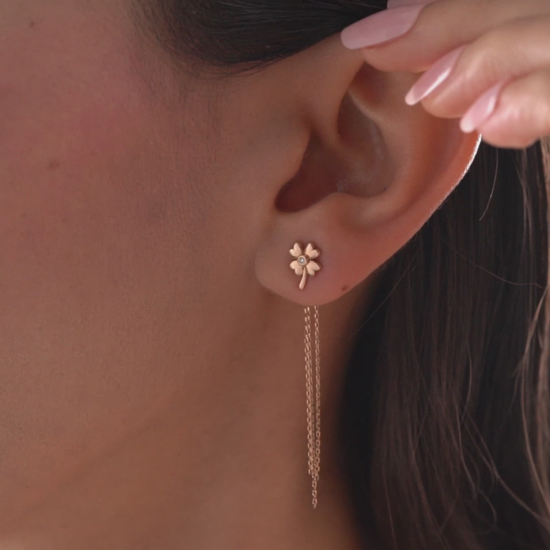 Arel Custom Jewelry 14k solid gold clover earrings with a center diamond and dangling chains on model's ear.