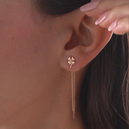 Arel Custom Jewelry 14k solid gold clover earrings with a center diamond and dangling chains on model's ear.