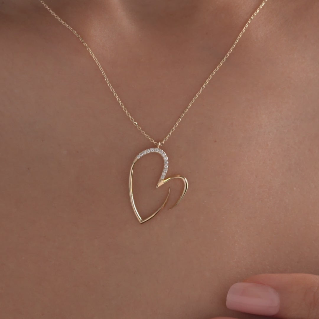 Arel Custom Jewelry 14k solid gold asymmetrical open heart necklace featuring half pave diamonds on a model.