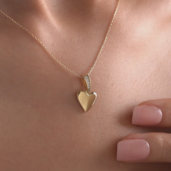 Arel Custom Jewelry 14k solid gold polished heart pendant featuring a pave diamond bail on a model.