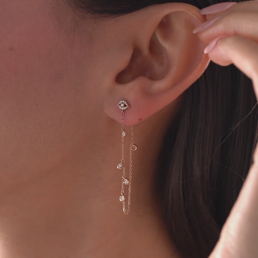 Arel Custom Jewelry 14k solid gold drape chain earring featuring a pave diamond evil eye stud and bezel diamonds on a model.