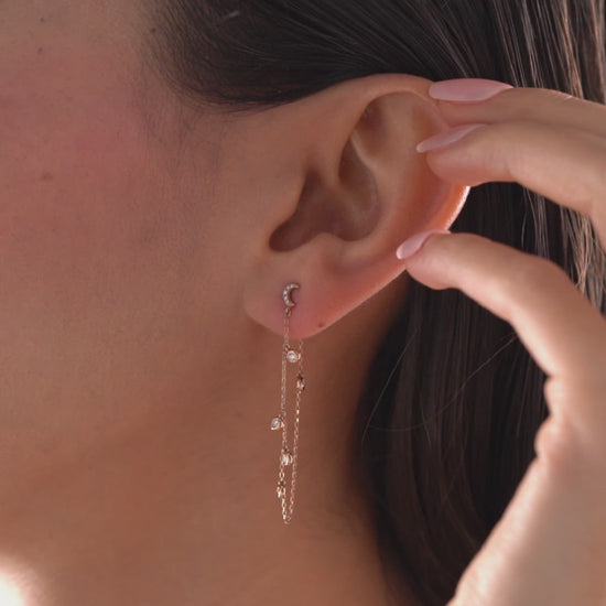 14k solid gold drape chain earring featuring a pave diamond crescent moon stud and bezel diamonds on a model