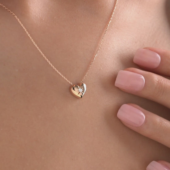 Arel Custom Jewelry 14k solid gold necklace featuring a polished puffed heart pendant with a starburst set center diamond on a model.