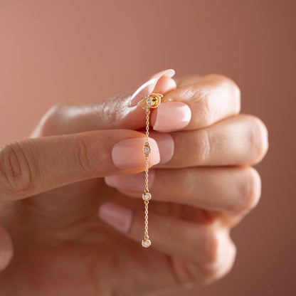 Arel Custom Jewelry 14k solid gold celestial crescent moon drop earring with dangling bezel set diamonds on a model.