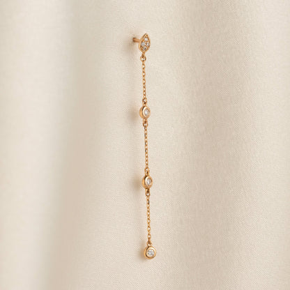 Arel Custom Jewelry 14k solid gold teardrop earring with natural diamonds on a dangling chain, worn by a model.