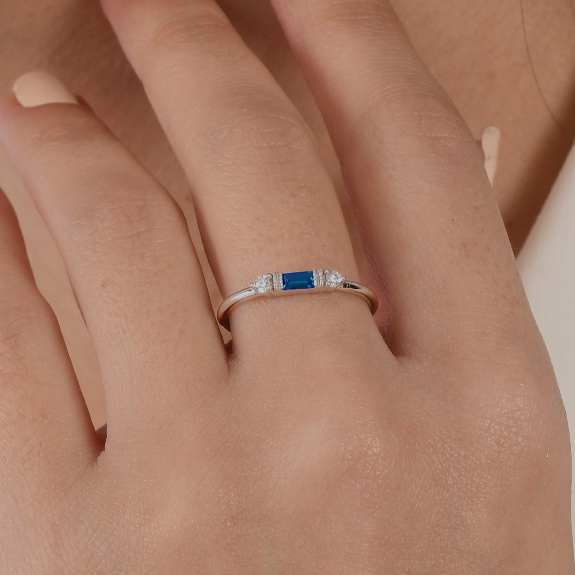 14k solid gold three stone ring featuring a 4x2mm center baguette gemstone and two 1.80mm round diamond accents on a model's hand.