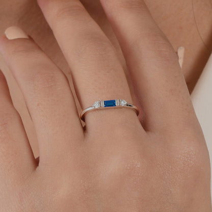 14k solid gold three stone ring featuring a 4x2mm center baguette gemstone and two 1.80mm round diamond accents on a model's hand.