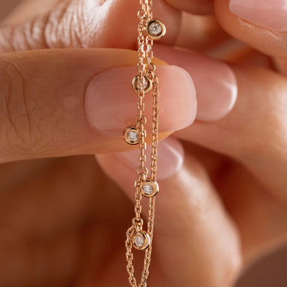 14k solid gold chain bezel earring featuring a round diamond stud and 5 diamond drops on a model.