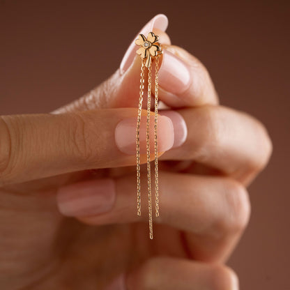 Arel Custom Jewelry 14k solid gold clover earrings with a center diamond and dangling chains on model's ear.