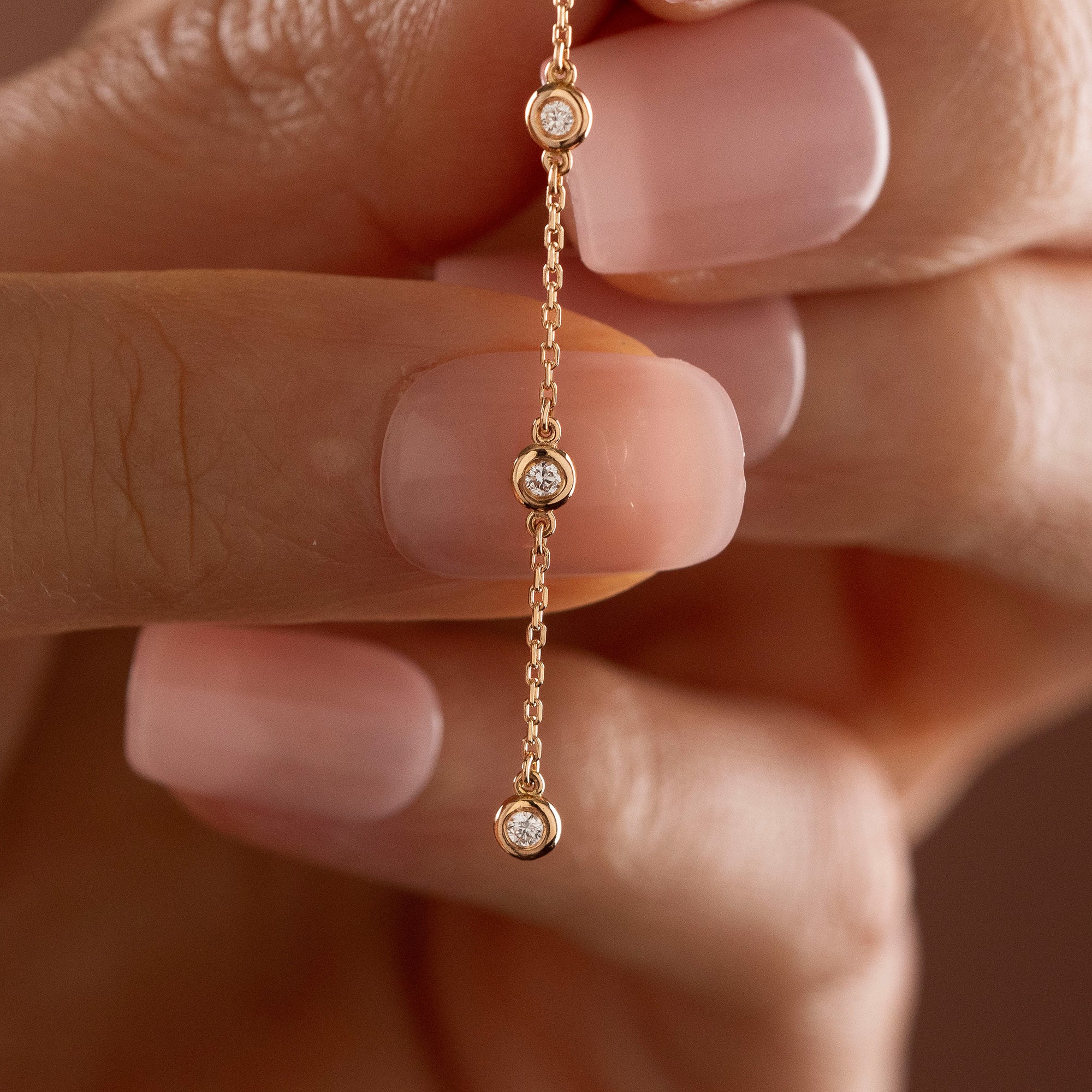Arel Custom Jewelry 14k solid gold diamond star drop earring with dangling bezel set diamonds on a model.