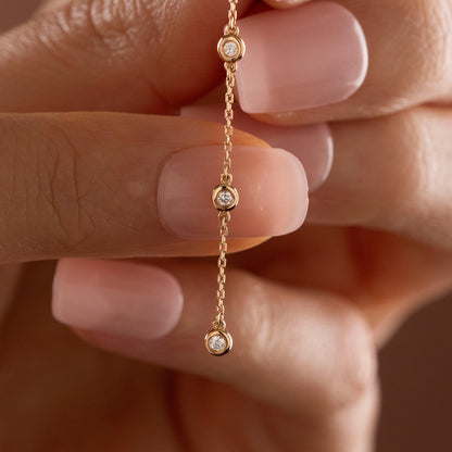 Arel Custom Jewelry 14k solid gold diamond star drop earring with dangling bezel set diamonds on a model.