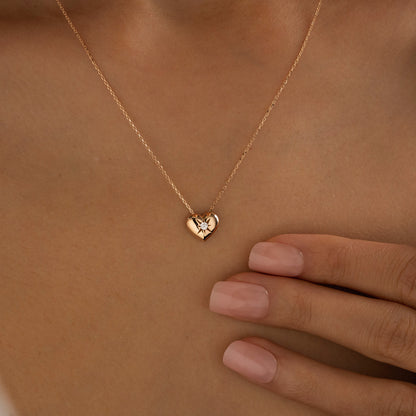 Arel Custom Jewelry 14k solid gold necklace featuring a polished puffed heart pendant with a starburst set center diamond on a model.