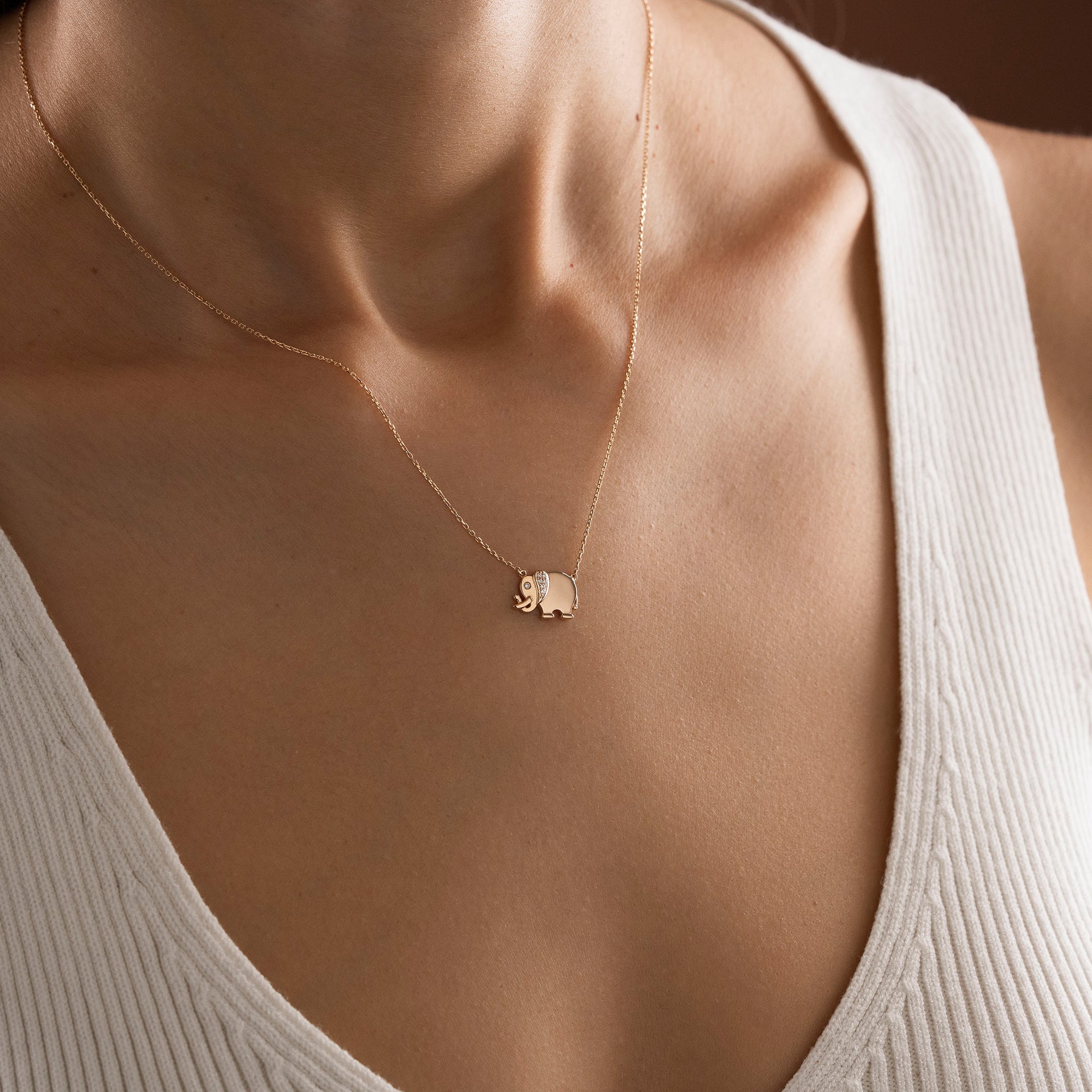 Arel Custom Jewelry 14k solid gold necklace featuring a polished elephant pendant with a pave diamond ear and trunk up on a model.
