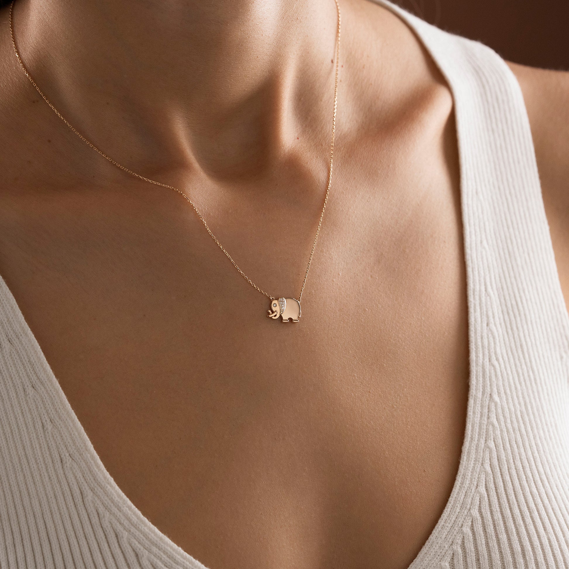 Arel Custom Jewelry 14k solid gold necklace featuring a polished elephant pendant with a pave diamond ear and trunk up on a model.