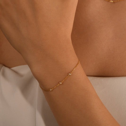 Arel Custom Jewelry 14k solid gold dainty station bracelet featuring three bezel set natural diamonds on a model's wrist