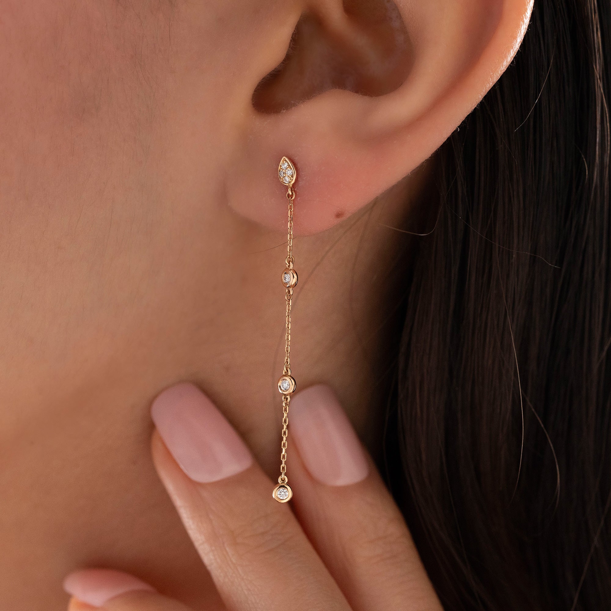 Arel Custom Jewelry 14k solid gold teardrop earring with natural diamonds on a dangling chain, worn by a model.