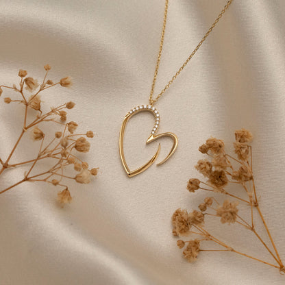 Arel Custom Jewelry 14k solid gold asymmetrical open heart necklace featuring half pave diamonds on a model.